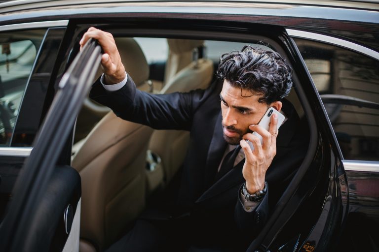Business man exiting a limousine while talking on his mobile telephone