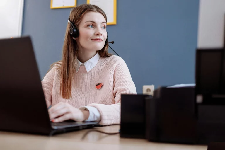 Woman with a headset sitting at a desk behind a computer