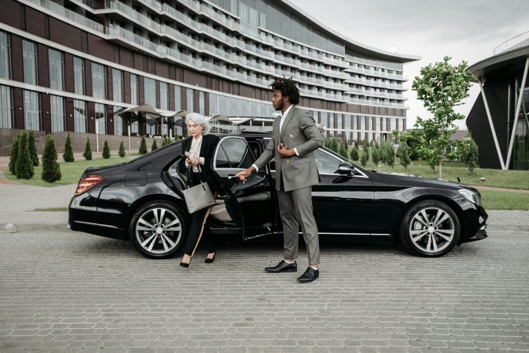 Chauffeur opening car door for female passenger